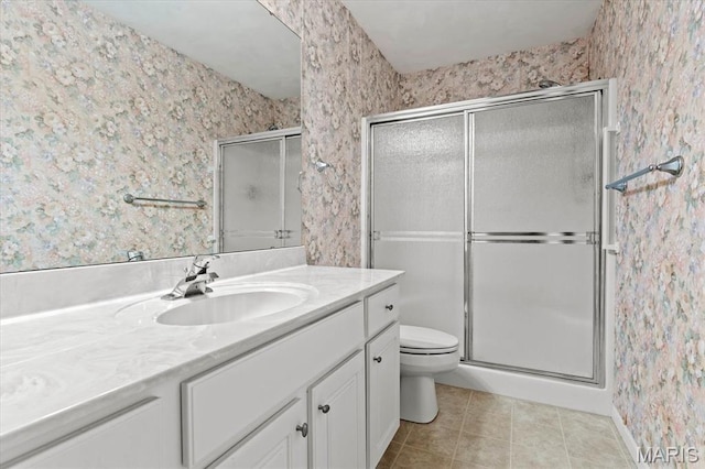 full bath with wallpapered walls, a stall shower, tile patterned floors, toilet, and vanity