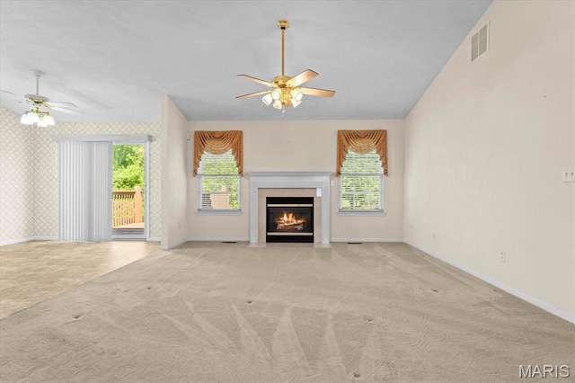 unfurnished living room with ceiling fan, carpet flooring, baseboards, healthy amount of natural light, and wallpapered walls