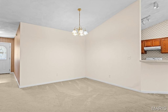 unfurnished dining area with light colored carpet, baseboards, a chandelier, and track lighting