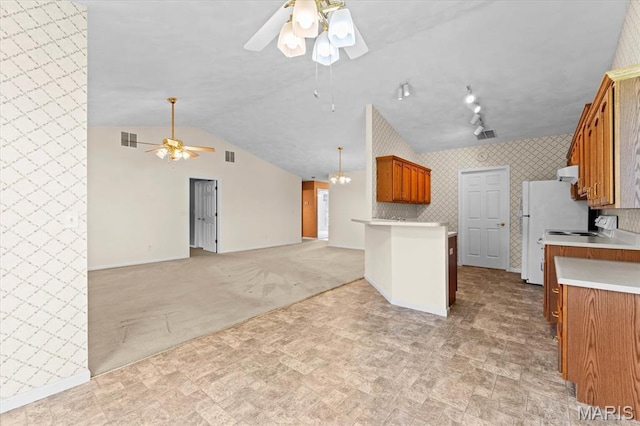 kitchen featuring a ceiling fan, brown cabinetry, open floor plan, vaulted ceiling, and light countertops