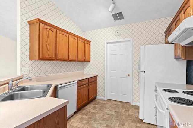 kitchen featuring white appliances, a sink, under cabinet range hood, light countertops, and brown cabinets