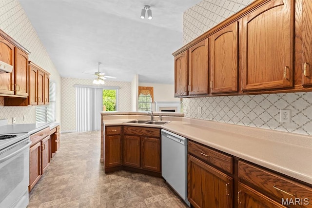 kitchen featuring white appliances, wallpapered walls, a sink, ceiling fan, and decorative backsplash
