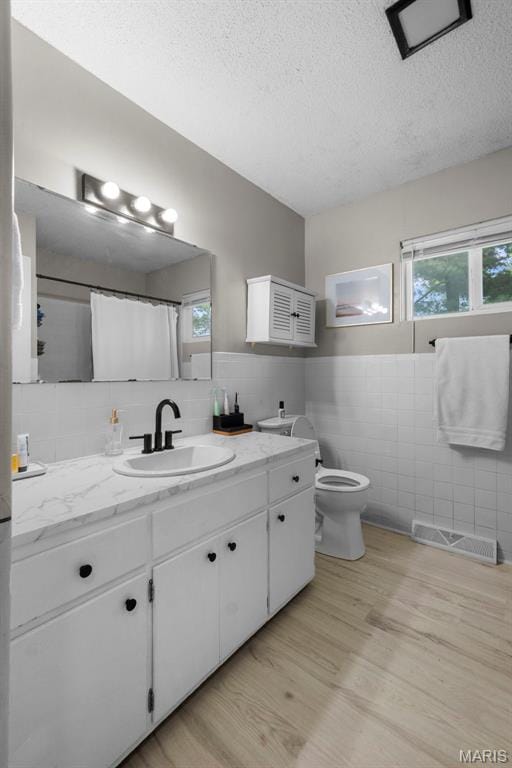 804 Harvard St, Sikeston, MO 63801 - full bath featuring tile walls, wood finished floors, a textured ceiling, toilet, and vanity