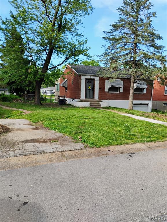 bungalow-style house with a front lawn, entry steps, brick siding, and an attached garage