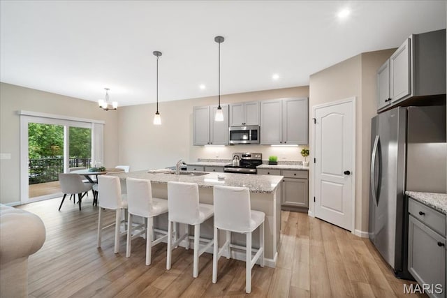 719 Myatt Dr, Wentzville, MO 63385 - kitchen featuring appliances with stainless steel finishes, gray cabinetry, light wood-style flooring, an island with sink, and a breakfast bar area