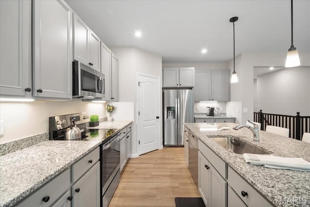 719 Myatt Dr, Wentzville, MO 63385 - kitchen featuring stainless steel appliances, light wood-style floors, pendant lighting, light stone counters, and gray cabinetry