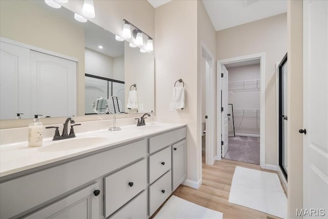 719 Myatt Dr, Wentzville, MO 63385 - bathroom with a shower stall, double vanity, wood finished floors, and a walk in closet