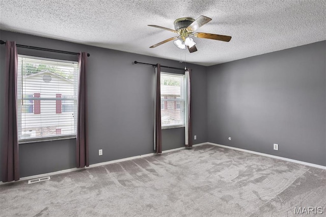 unfurnished room with a textured ceiling, carpet floors, a ceiling fan, and baseboards