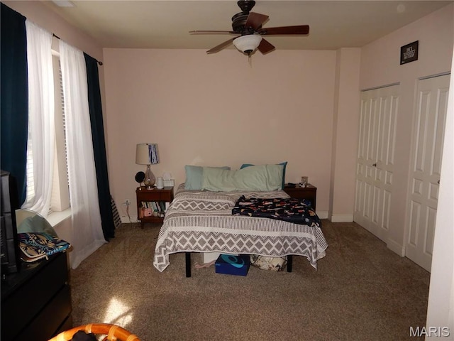 bedroom featuring carpet, two closets, and a ceiling fan