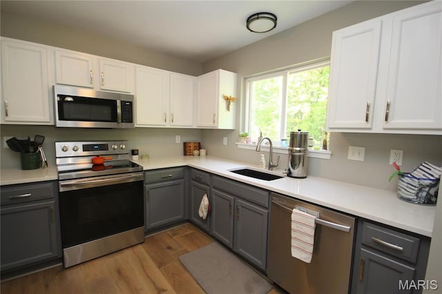 1209 Hunters Chase Dr, Eureka, MO 63025 - kitchen with appliances with stainless steel finishes, gray cabinets, a sink, dark wood-style floors, and white cabinetry