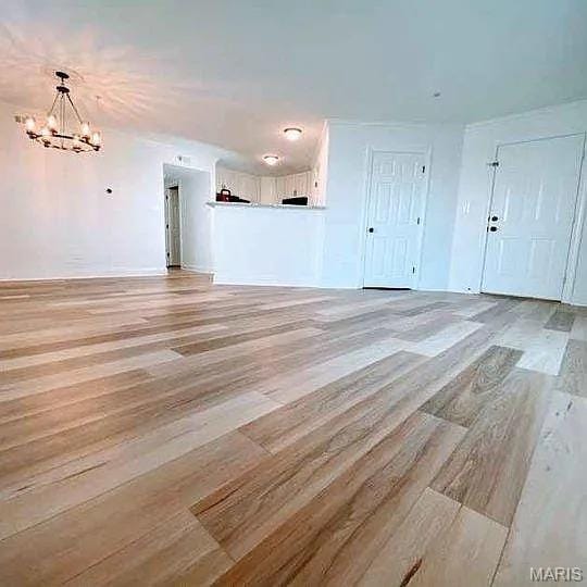 14 Homefield Gardens Dr Unit 19N, Ofallon, MO 63366 - unfurnished living room with a chandelier, light wood-type flooring, and baseboards