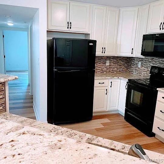 14 Homefield Gardens Dr Unit 19N, Ofallon, MO 63366 - kitchen with black appliances, white cabinetry, and light wood finished floors