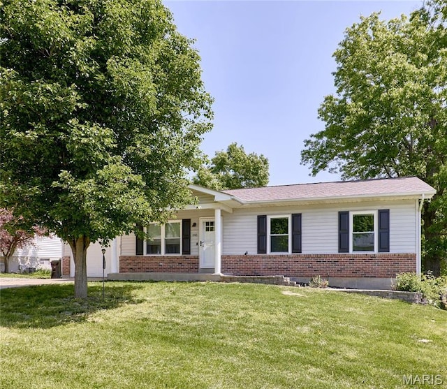 view of front of home with brick siding, a front lawn, a porch, and concrete driveway