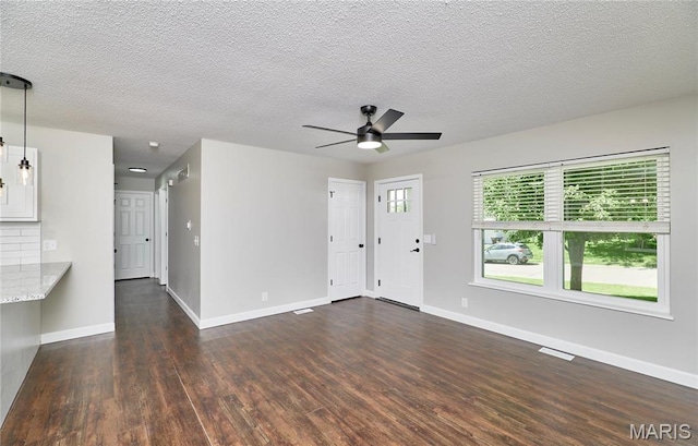 unfurnished living room featuring dark wood-type flooring, baseboards, ceiling fan, and a textured ceiling
