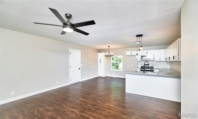 kitchen featuring white microwave, a chandelier, dark wood-style flooring, a sink, and a textured ceiling