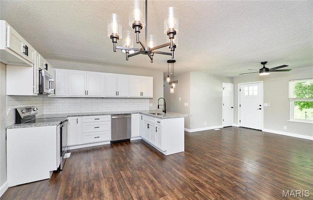kitchen featuring appliances with stainless steel finishes, a sink, a peninsula, a chandelier, and backsplash