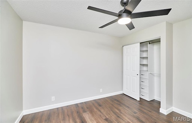 unfurnished bedroom with dark wood-type flooring, a closet, a textured ceiling, and baseboards