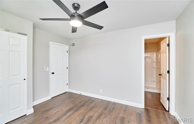 unfurnished bedroom featuring dark wood-type flooring, a textured ceiling, baseboards, ceiling fan, and connected bathroom