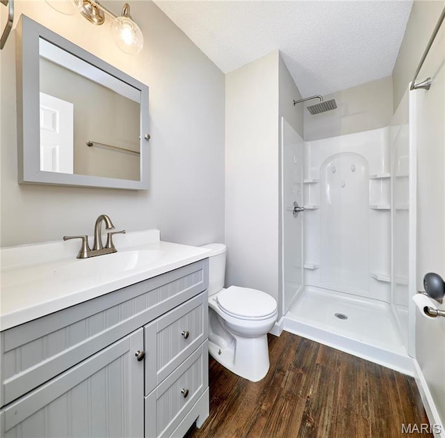 full bathroom with wood finished floors, a shower, vanity, toilet, and a textured ceiling