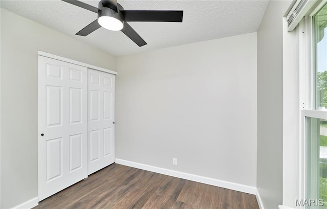 unfurnished bedroom featuring dark wood finished floors, baseboards, a closet, ceiling fan, and a textured ceiling