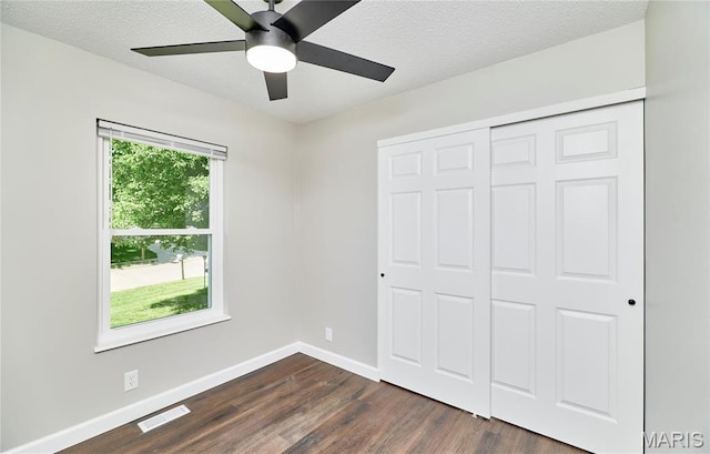 unfurnished bedroom featuring dark wood-style flooring, baseboards, a closet, a textured ceiling, and ceiling fan