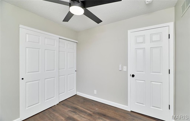 unfurnished bedroom featuring dark wood finished floors, a closet, baseboards, ceiling fan, and a textured ceiling