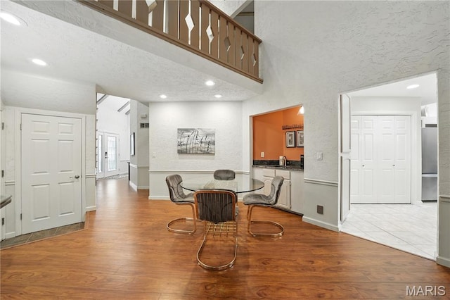 dining space with wood finished floors, baseboards, recessed lighting, and a towering ceiling