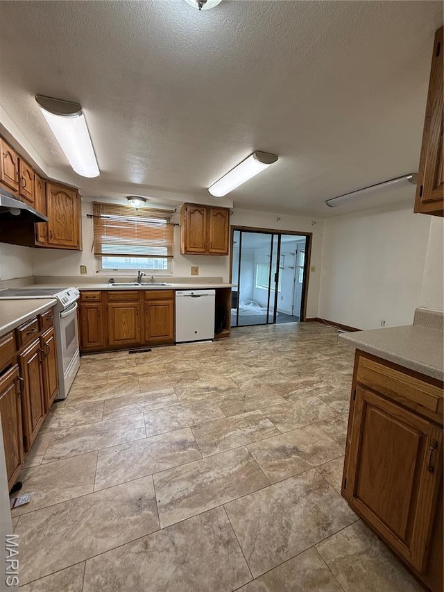 226 Dixie St, Sikeston, MO 63801 - kitchen with white appliances, a sink, brown cabinets, under cabinet range hood, and light countertops