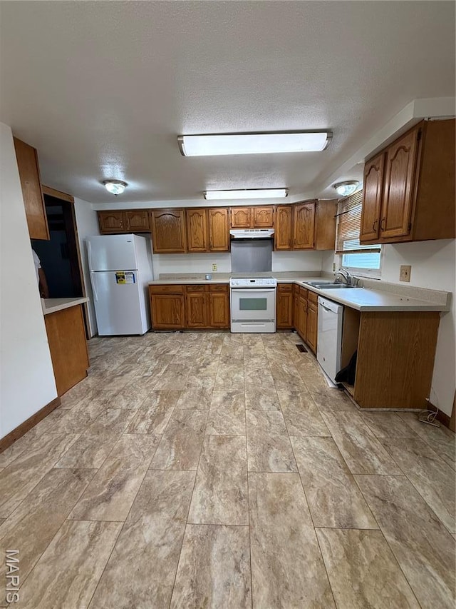 226 Dixie St, Sikeston, MO 63801 - kitchen with white appliances, brown cabinets, a sink, light countertops, and under cabinet range hood