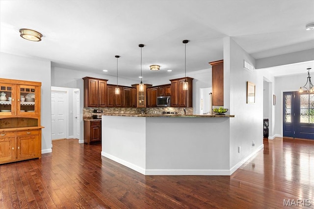 1438 Arbor Green Trl, Ofallon, IL 62269 - kitchen featuring stainless steel microwave, dark wood-style flooring, backsplash, dark stone countertops, and hanging light fixtures