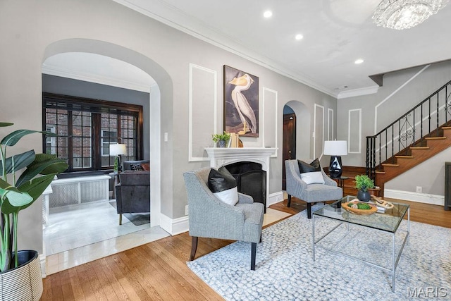 316 Melville Ave, Saint Louis, MO 63130 - living room with wood finished floors, a fireplace, ornamental molding, stairway, and arched walkways