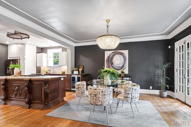 316 Melville Ave, Saint Louis, MO 63130 - dining area featuring a chandelier, wine cooler, light wood finished floors, crown molding, and baseboards