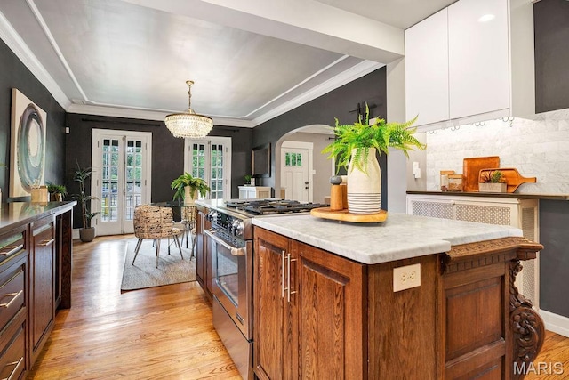 316 Melville Ave, Saint Louis, MO 63130 - kitchen with gas stove, light wood-style floors, arched walkways, tasteful backsplash, and light countertops