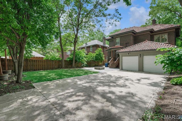316 Melville Ave, Saint Louis, MO 63130 - view of front of property featuring a tile roof, a chimney, stucco siding, an outdoor fire pit, and a garage