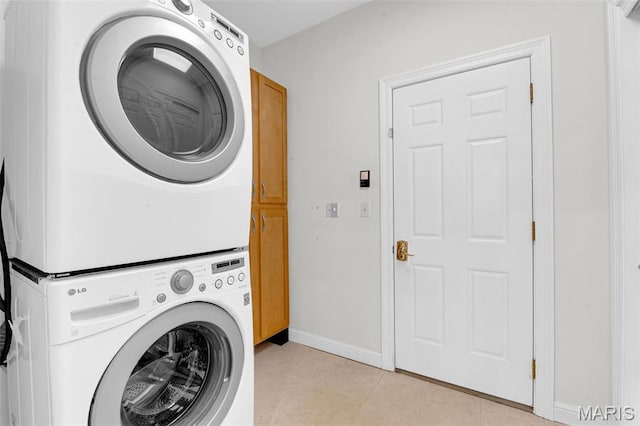 1204 Cobblestone Ter, Lake St Louis, MO 63367 - clothes washing area featuring stacked washer / dryer, cabinet space, baseboards, and light tile patterned flooring