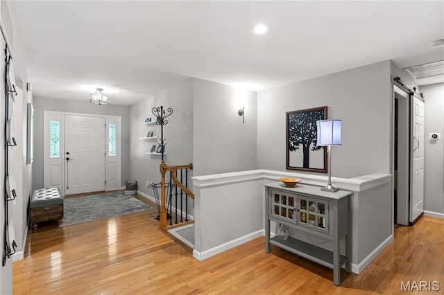 entrance foyer with a barn door, light wood finished floors, baseboards, recessed lighting, and a chandelier