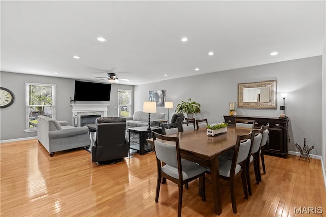 dining area with a ceiling fan, healthy amount of natural light, light wood-style flooring, a high end fireplace, and recessed lighting