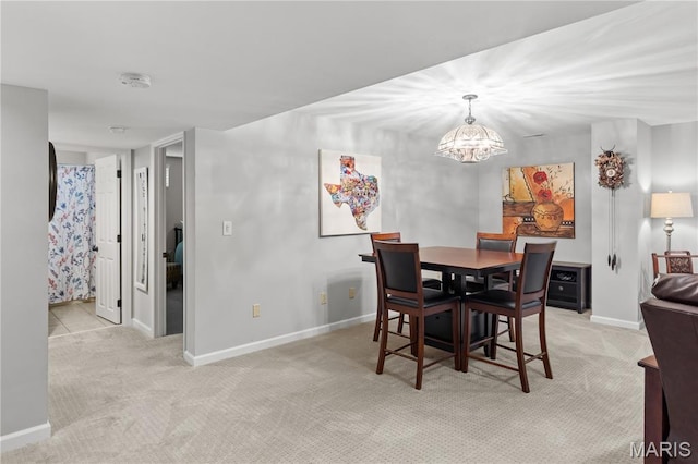 dining area featuring light colored carpet, baseboards, and a chandelier
