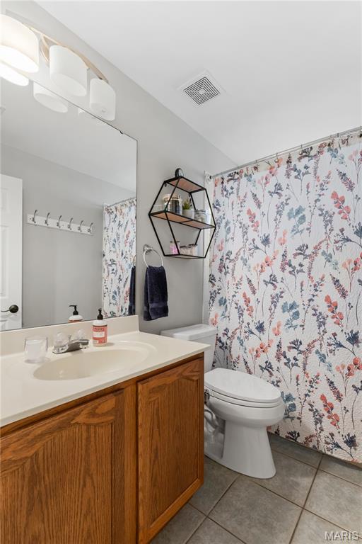 bathroom featuring tile patterned floors, toilet, vanity, and curtained shower