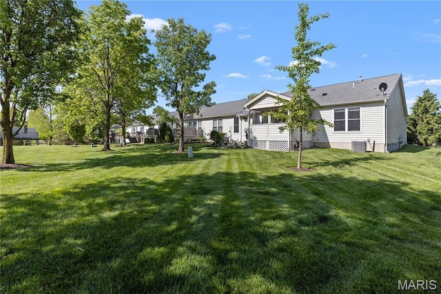 view of green lawn with central AC unit