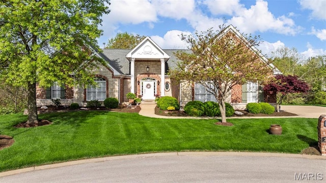 greek revival inspired property featuring stone siding and a front lawn