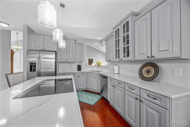 kitchen featuring stainless steel appliances, glass insert cabinets, gray cabinets, dark wood-style floors, and decorative light fixtures