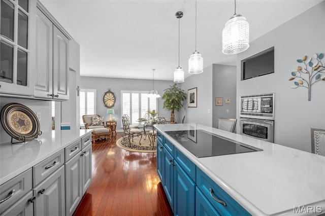 kitchen with appliances with stainless steel finishes, a chandelier, light countertops, glass insert cabinets, and dark wood-style floors