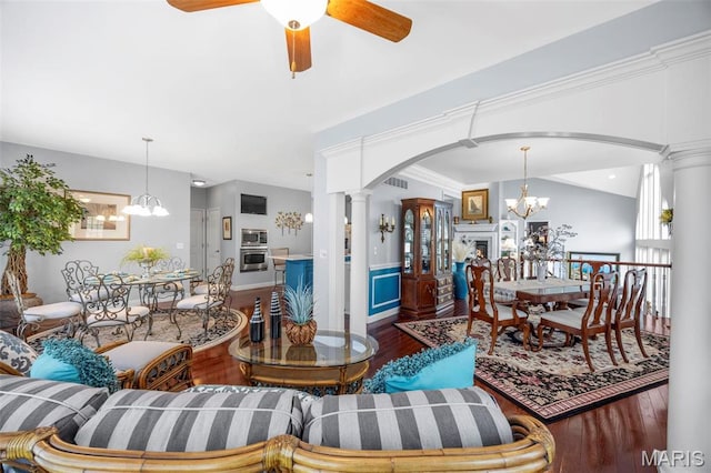 living area with a chandelier, ornate columns, wood finished floors, arched walkways, and a ceiling fan