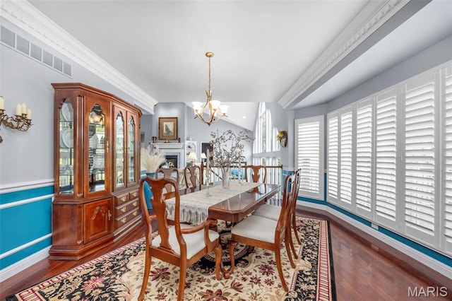 dining space featuring wood finished floors, a chandelier, baseboards, and a fireplace