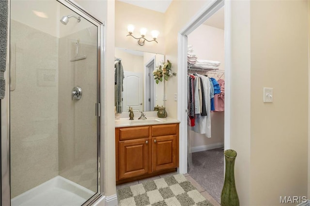 full bath with a stall shower, vanity, a walk in closet, and baseboards