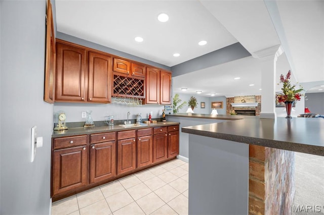 indoor wet bar with a brick fireplace, recessed lighting, light tile patterned floors, and decorative columns