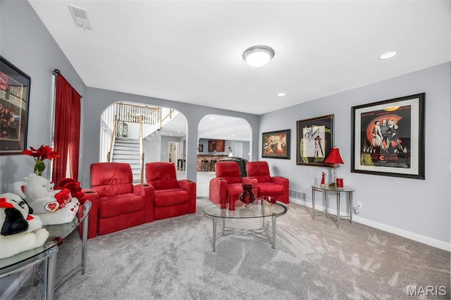 carpeted living room with arched walkways, stairway, baseboards, and recessed lighting