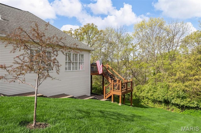 view of side of home featuring stairway, a shingled roof, a wooden deck, and a yard