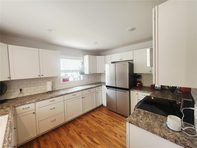 1104 Ringo St, Mexico, MO 65265 - kitchen with freestanding refrigerator, decorative backsplash, light wood-style flooring, and white cabinetry